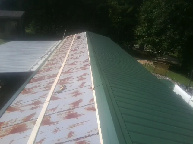Old rusted panels beside newly installed green metal roofing — Wind Damage Roof Repair by Roofing Brothers in Pompano Beach