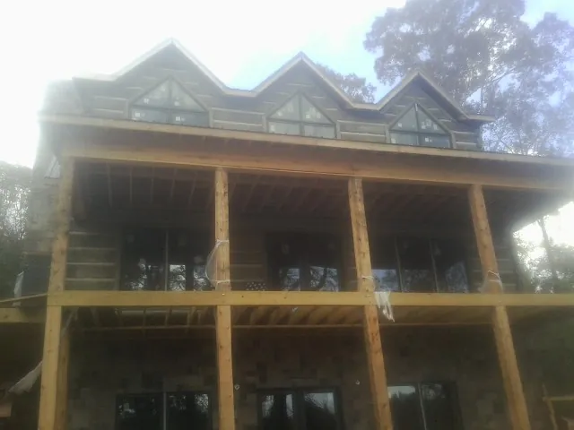 Dormers and porch framing on a large log home under construction — Roof Coating work by our crew in Pompano Beach