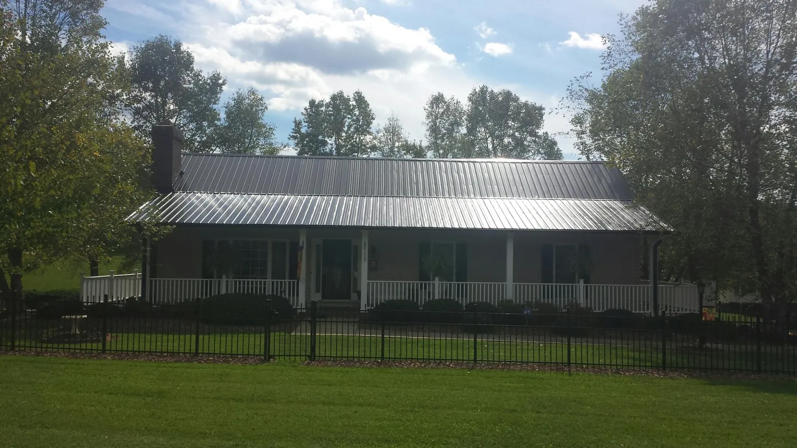 Gray metal roof on a brick ranch with a full width front porch — Gutter Guard Installation work by our crew in Pompano Beach