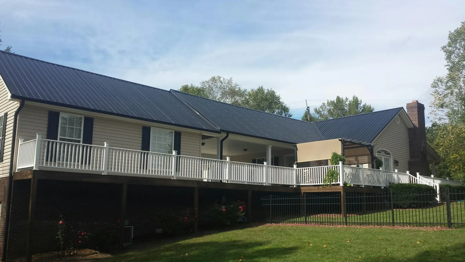 Black metal roof above a long white railed deck on a hillside home in Pompano Beach