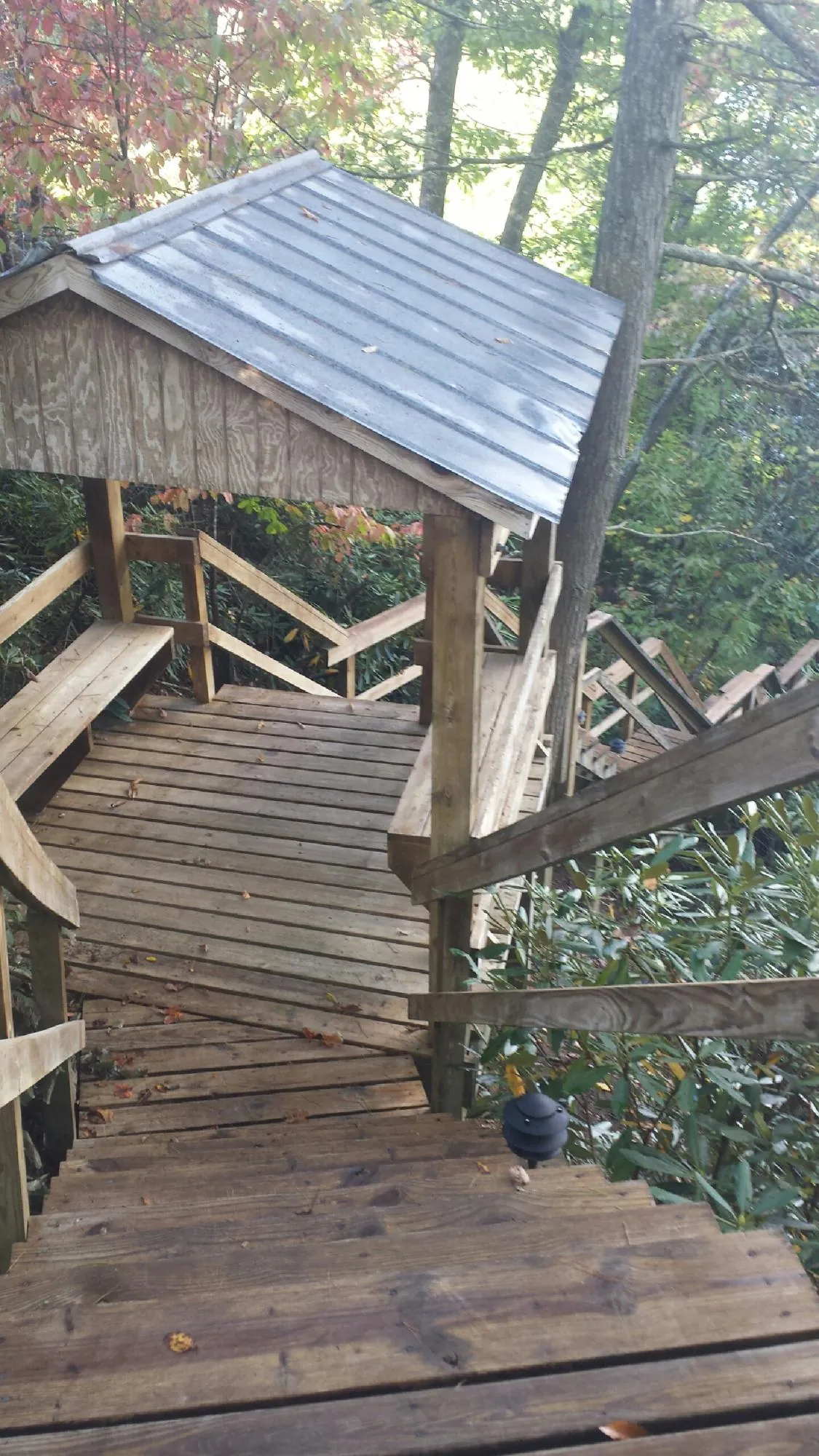 Metal roofed shelter over wooden steps on a wooded walkway — Skylight Repair & Installation work by our crew in Pompano Beach