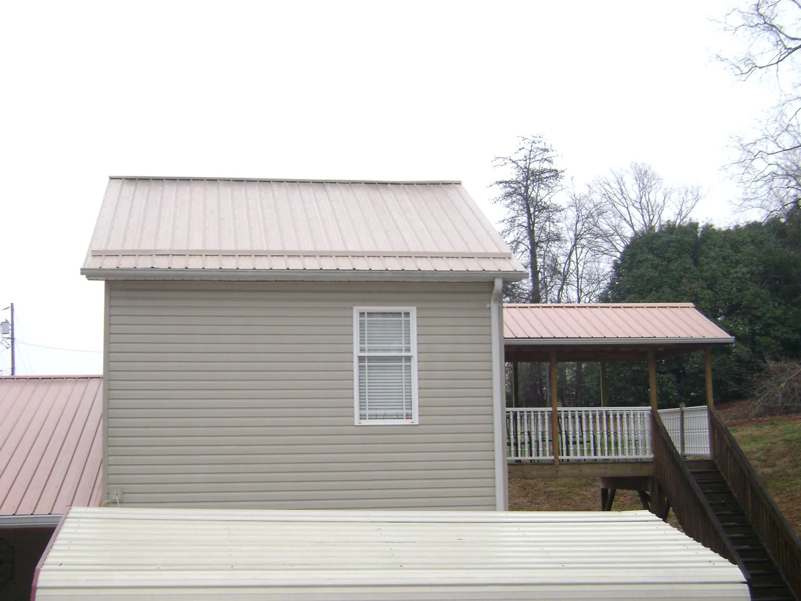 Tan metal roofs on a two story addition and attached porch, from a Roof Replacement job in Pompano Beach