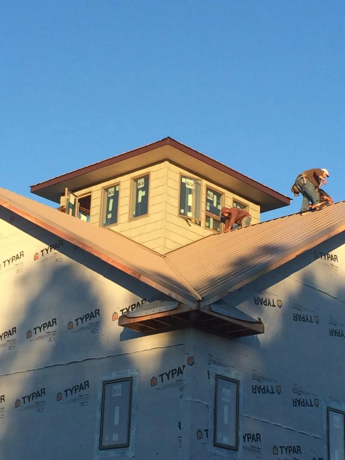 Roofers working around a rooftop cupola on a new metal roof at sunset — Roof Waterproofing in Pompano Beach by Roofing Brothers